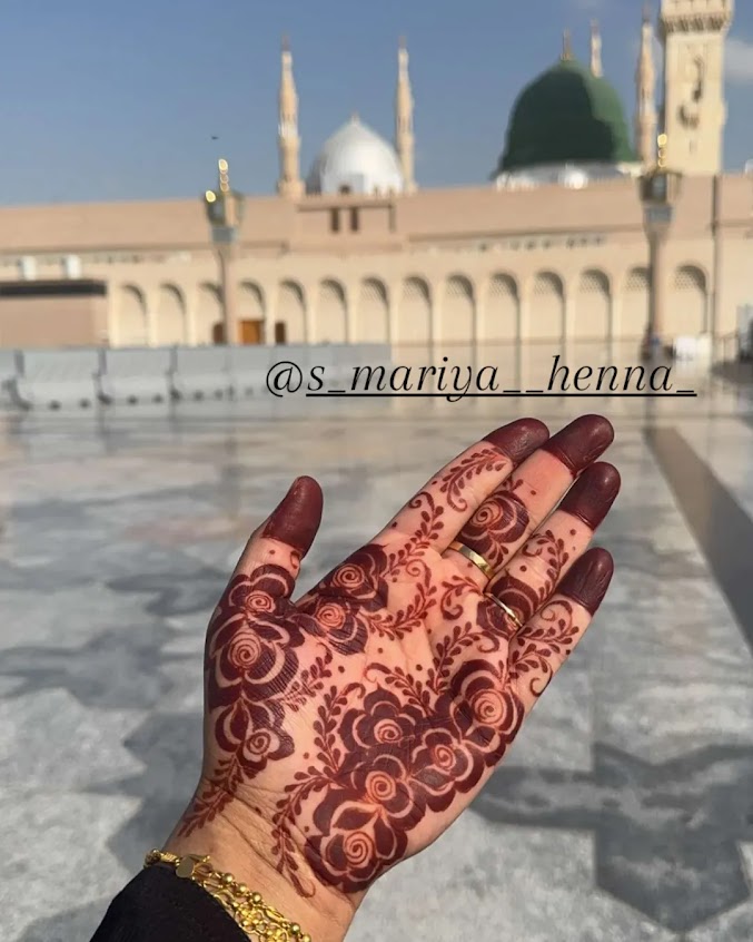 Henna design on a hand with Al-Masjid an-Nabawi in the background